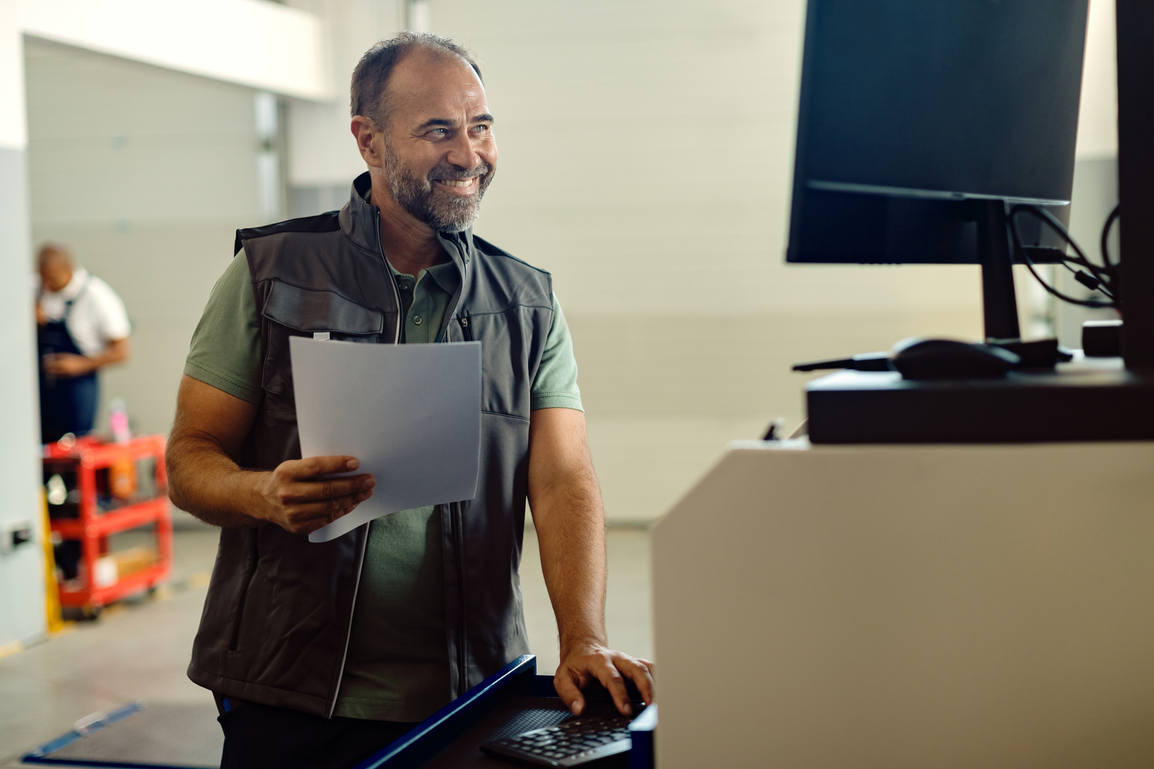happy-mid-adult-mechanic-working-computer-auto-repair-shop